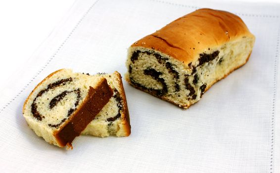 cut baked roll with poppy seeds on white napkin