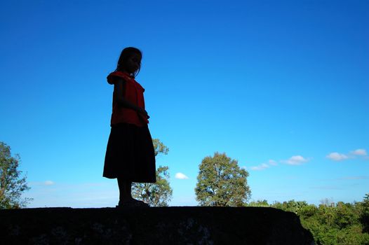 A cambodian girl standing on a large stone step of a temple