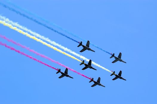 Six aircrafts in the blue sky making colour smoke