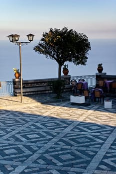 Coffee tables on terrace overlooking Mediterranean sea at sunset