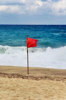 Red flag on beach with stormy weather