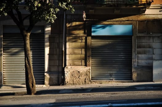 Italian street at sunset with tree and closed shops