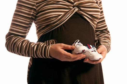 The pregnant woman on a white background. In hands holds small boots