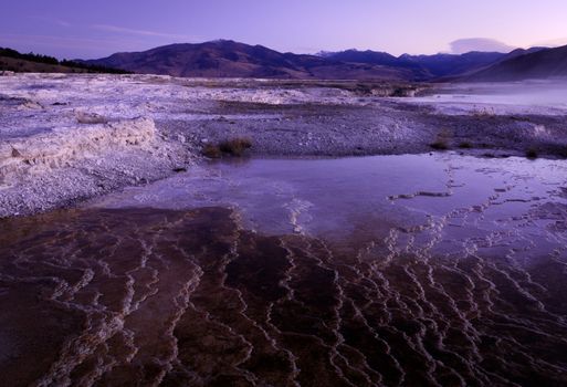 The Upper Terraces of Mammoth Hot Springs and distant mountains before sunrise, Yellowstone National Park, Wyoming, USA