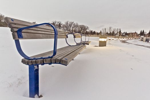 A park bench in the snow by the shores of Wascana Lake