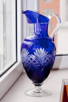 A vintage glass blue vase on a white sill
