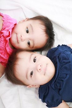 Twin baby sisters lay down in the bed