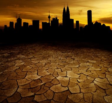 A city looks over a desolate cracked earth landscape in sunset