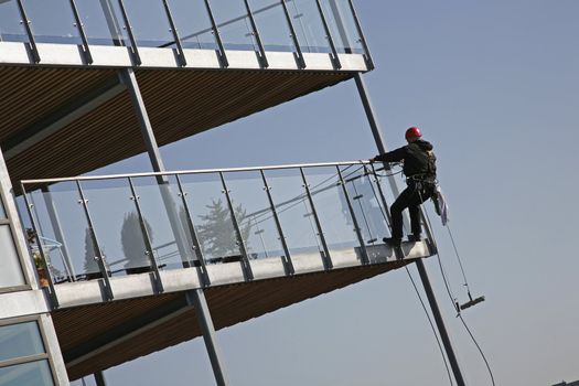 Climber cleaning glass around a waterfront balcony -Nyborg - Denmark.