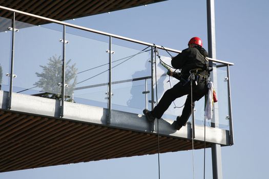 Climber cleaning glass around a waterfront balcony -Nyborg - Denmark.