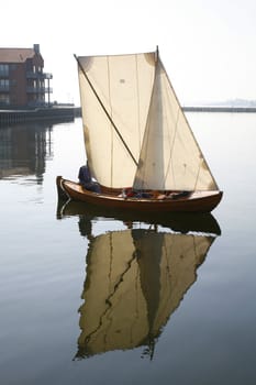 Dinghy in morning mist and very little wind. Western harbour of Nyborg, Denmark.