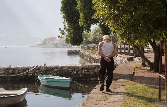 Fisherman walking along the coastline of Montenegro by the Adriatic Sea an early morning at summertime.