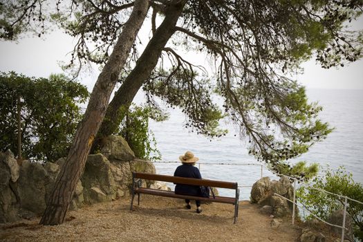 Mature female with hat on bench with view by the sea - Moschenica Draga - Croatia.