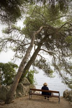 Mature female with hat on bench with view by the sea - Moschenica Draga - Croatia.