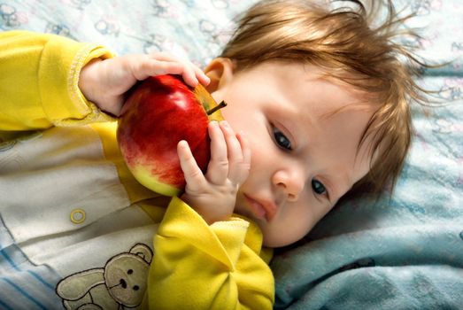 Beautiful baby with ripe red apple in her hand.