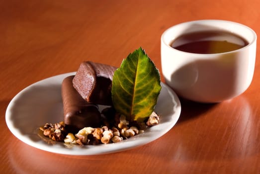 Cup of tea and saucer with sweet dessert of chocolate snacks.