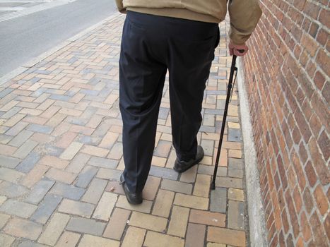 Elderly man walking along the pavement.