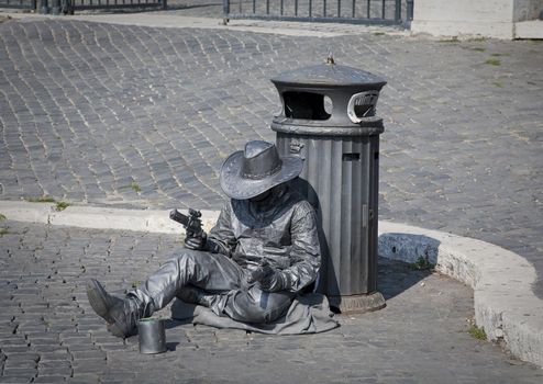 SILVER GUN MAN ROME, ROME, ITALY, SEPTEMBER 29, 2011:  Street performer dressed like a sleeping silver cowboy performs in the street in front of Castel Sant Angelo, Rome, Italy