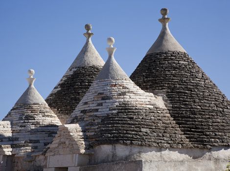 The roof of a rural trullo villa against a blue sky - Italy. A trullo is a traditional Apulian stone dwelling with a conical roof. The style of construction is specific to Itria Valley.