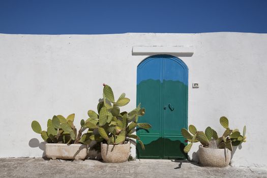 Nice painted door and wall in the Apulian town Ostuni, Italy on a hot September day with a nice blue sky.