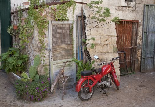 Red vintage Italian moped in old courtyard - Basilicata, Italy.