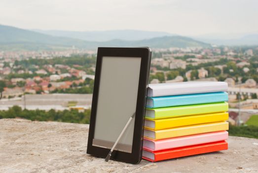 Stack of colorful books with electronic book reader