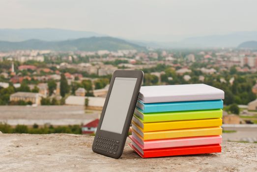 Stack of colorful books with electronic book reader