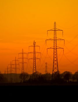 sunset over a field of highvoltage power towers 