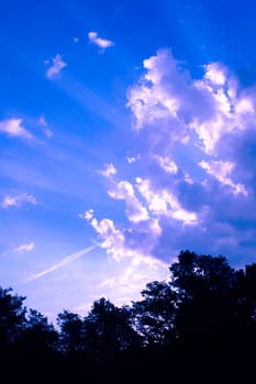 Sun beams passing through clouds in the blue sky