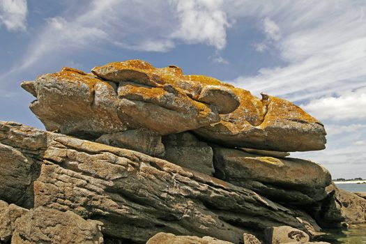 Rocks on the stone coast near Pointe de Trevignon, Brittany, North France. Stone with orange lichens.