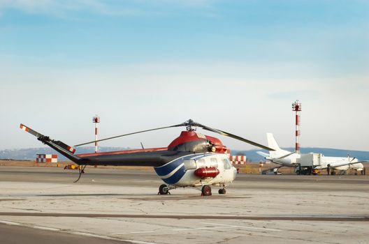 Airfield with helicopter and airplane an the background.