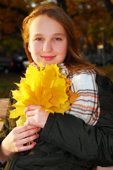 Portrait of a beautiful teenage girl with yellow fall maple leaves