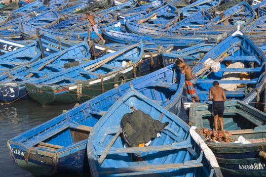 Young men at work on a fleet of wooden fishing boats in the fishing village of Essaouira, Morocco.