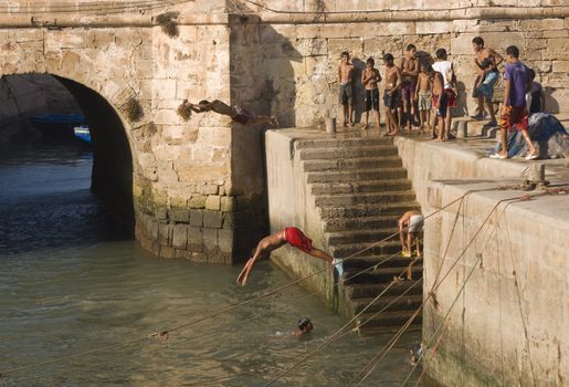 Group of boys diving into the harbour in the fishing village of Essaouira, Morocco.