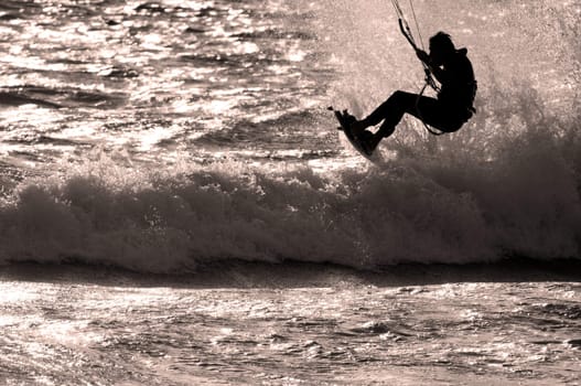Sillhouette of kite surfer jumping wave