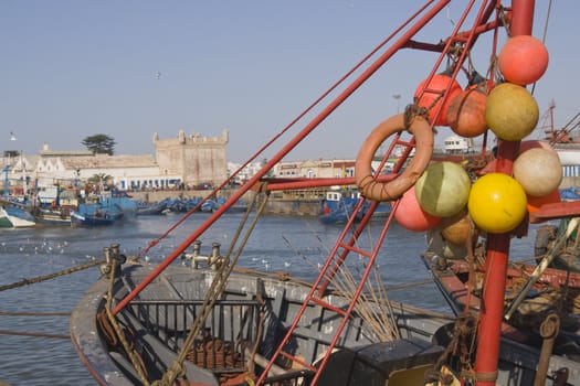 Fishing boat with colorful floats tied to the rigging in the fishing village of Essaouira, Morocco.