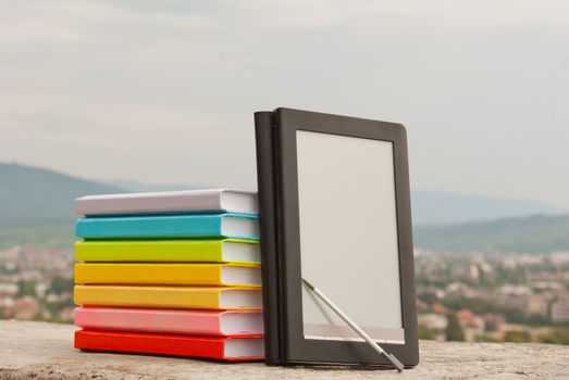 Stack of colorful books with electronic book reader