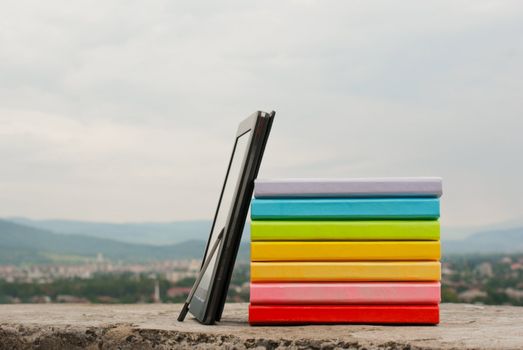 Stack of colorful books with electronic book reader