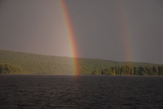 A rare double rainbow after a storm just passed over a lake.