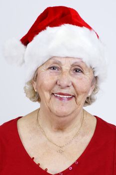Detailed close-up of a grandmother smiling as she prepares for Christmas with her red Santa Claus hat.
