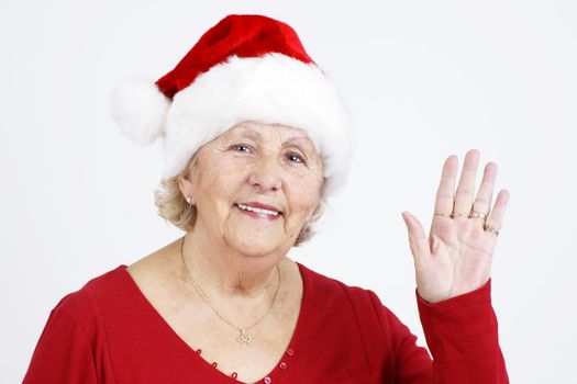 Grand-mother sending her love for Christmas by waving her hand while wearing Santa Claus hat.