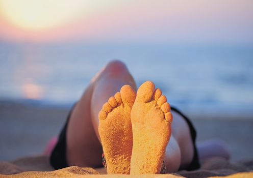 Female feet on the sandy beach at the sea