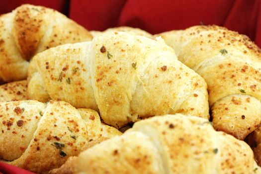 Delicious croissants  brushed with butter, and sprinkled with parmesan cheese and herbs. Selective focus on center croissant with shallow depth of field. Some blur on lower portion of image.