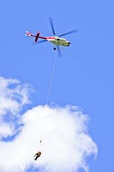 Rescue helicopter rescuing person by airlifting dangling on rope
