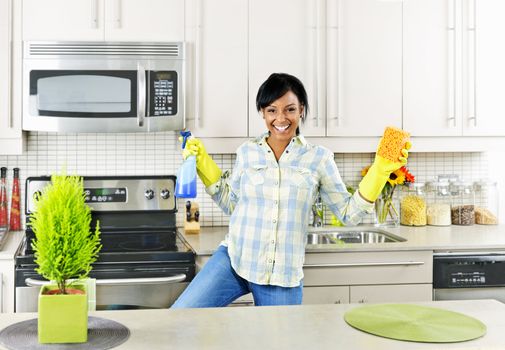 Smiling young black woman dancing and enjoying cleaning kitchen