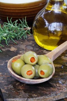 Spanish olives with olive oil and rosemary on a rustic slate background. 
