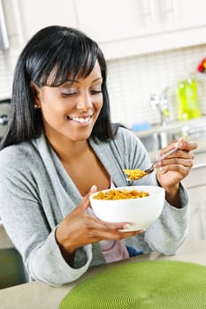 Smiling black woman having breakfast in modern kitchen interior