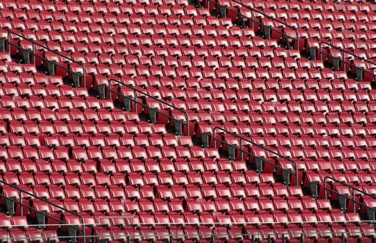 Red staduim seats cast in bright sunshine.