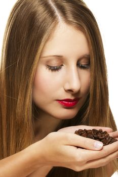 young woman scenting on a handful of coffee beans on white background