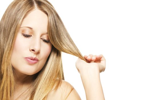 impishly blonde woman playing with her hairs on white background